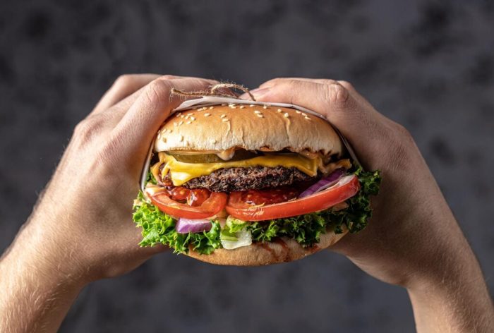 mãos segurando hambúrguer, representando as lanchonetes em São Paulo