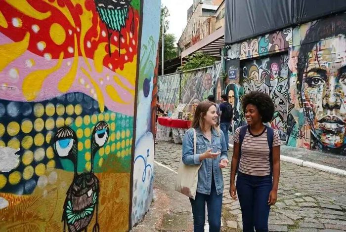 Estudantes caminham entre grafites no Beco do Batman, ponto cultural em um dos melhores bairros para estudantes em SP.