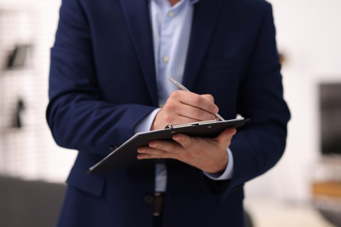 Profissional realizando vistoria de imóvel com prancheta, registrando condições da propriedade.