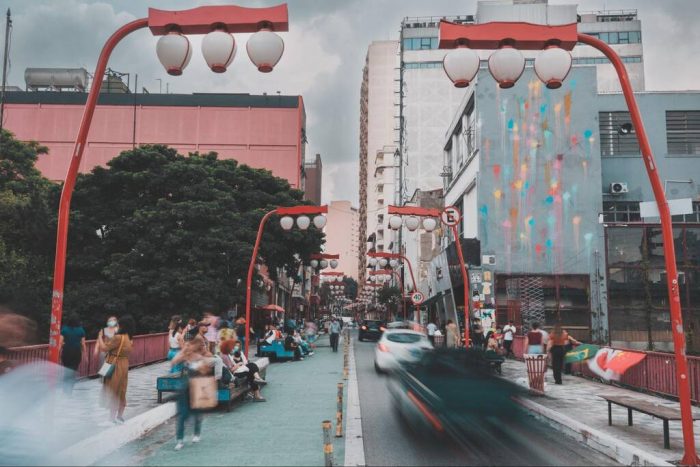 Passeios culturais em SP na Liberdade, com pedestres circulando pela tradicional rua decorada por luminárias orientais, um dos principais pontos de encontro da cultura japonesa na cidade.